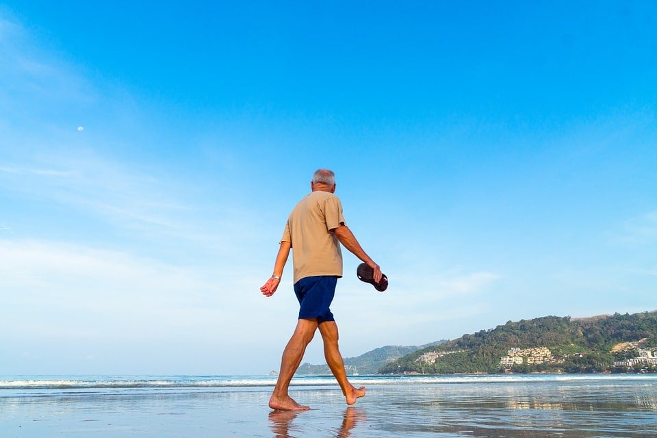 retiree walks on a beach